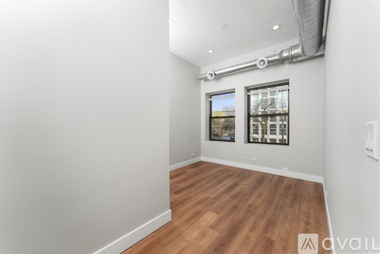 A room with wooden flooring and a window showing a view of a building.