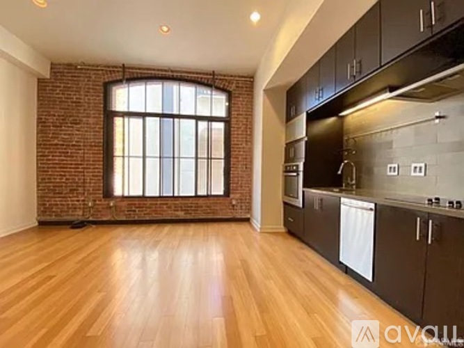 A kitchen with wooden floors and a brick wall.