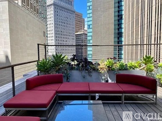 A red couch is on a balcony with a pool and plants.
