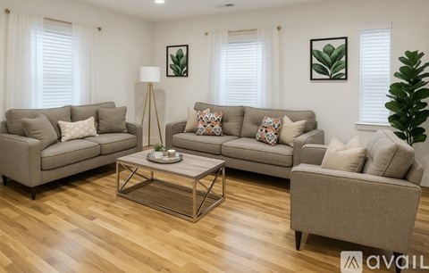 A living room with a grey sofa set and a wooden floor.