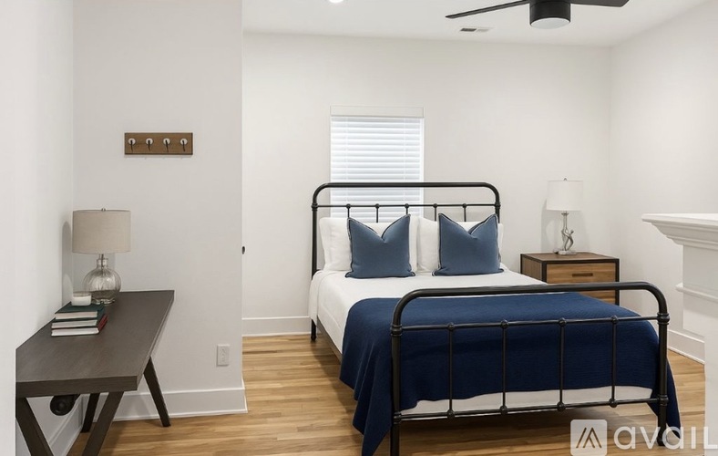 A bedroom with a bed, nightstand, and a table with a lamp on it.