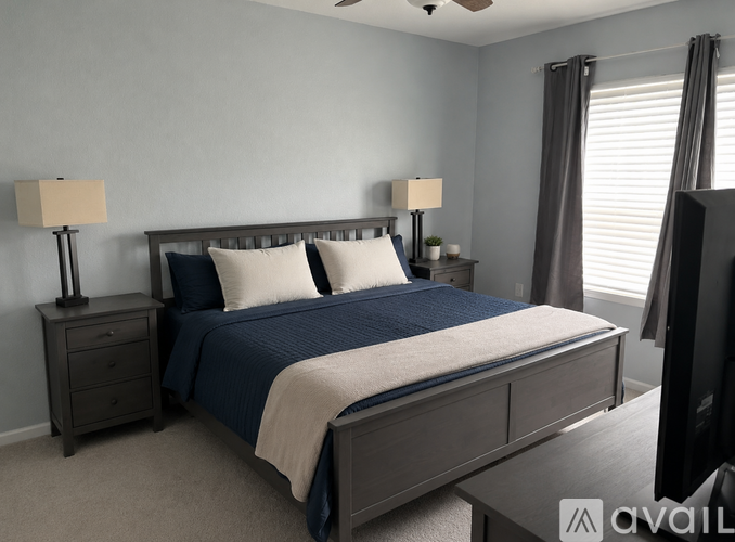 A bedroom with a bed, nightstands, and lamps.