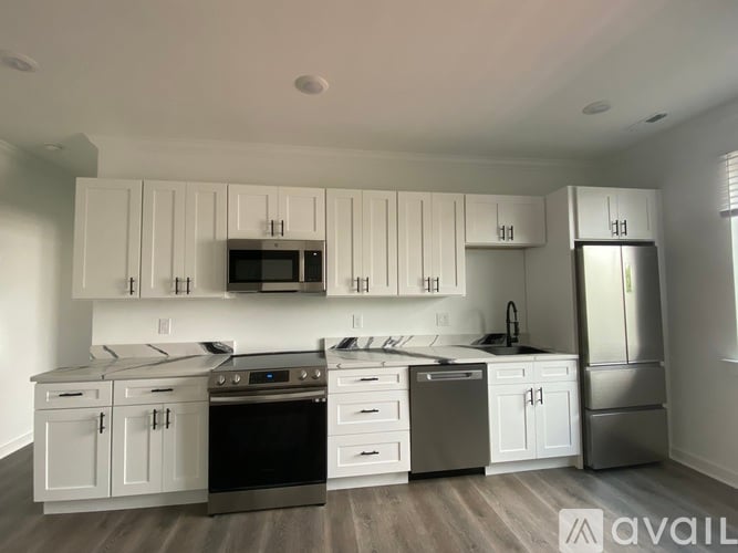 A modern kitchen with white cabinets and stainless steel appliances.