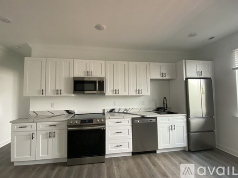 A modern kitchen with white cabinets and stainless steel appliances.