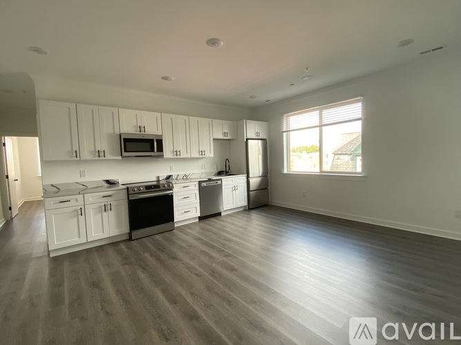 A spacious kitchen with white cabinets and a wooden floor.