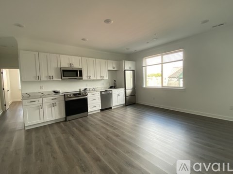 A spacious kitchen with white cabinets and a wooden floor.
