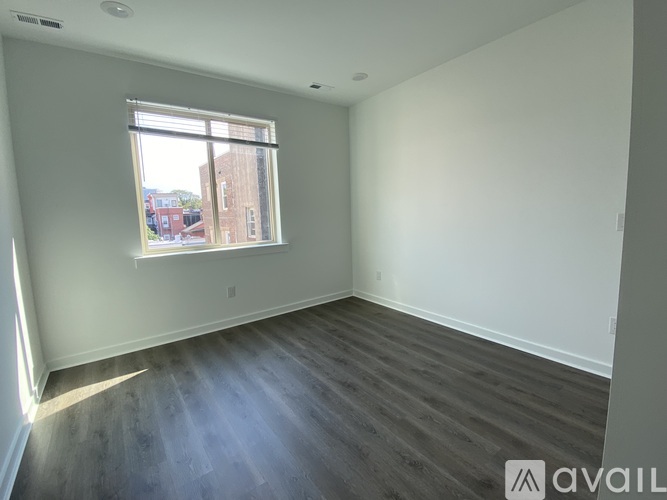 A room with a large window and wooden flooring is available for rent.