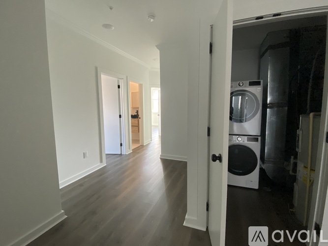 A long hallway with a washer and dryer in the doorway.