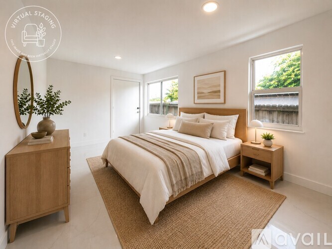 A bedroom with a large bed, a wooden nightstand, and a round mirror on the wall.