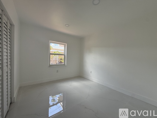 A room with a window and a view of a tree and a building outside.