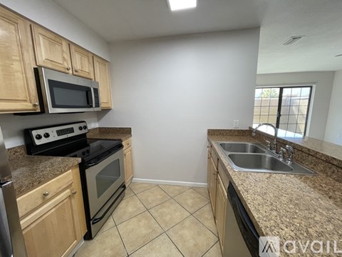 A kitchen with a black stove top oven and microwave, a sink, and beige cabinets.