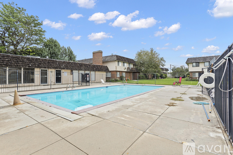 A pool surrounded by a concrete patio and a fence.