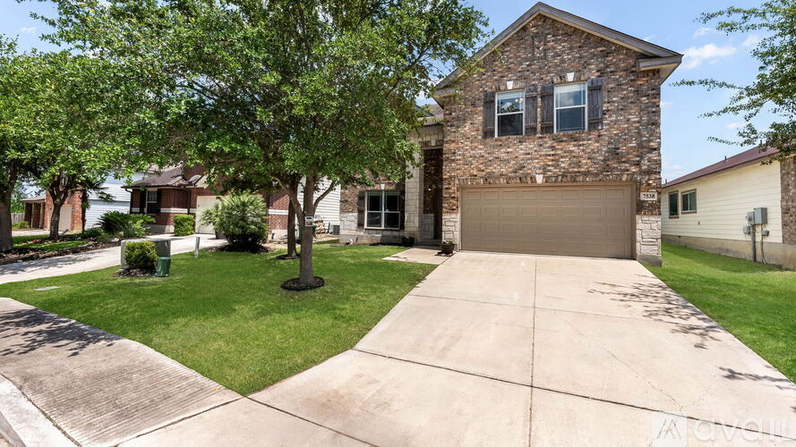 A house with a driveway and a tree in front.