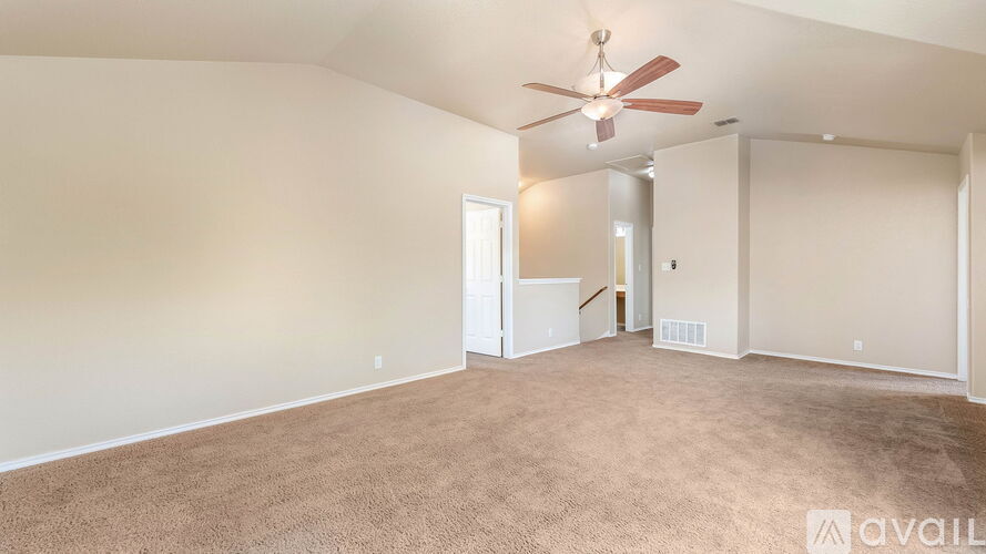 A spacious room with a carpeted floor and a ceiling fan.