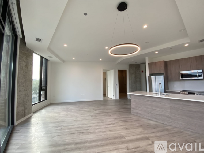 A spacious, well-lit room with a kitchen area and a large window.