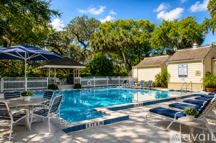 A pool with a blue umbrella and chairs around it.