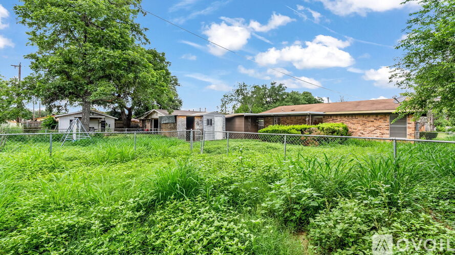 A grassy field with a fence and a house in the background.