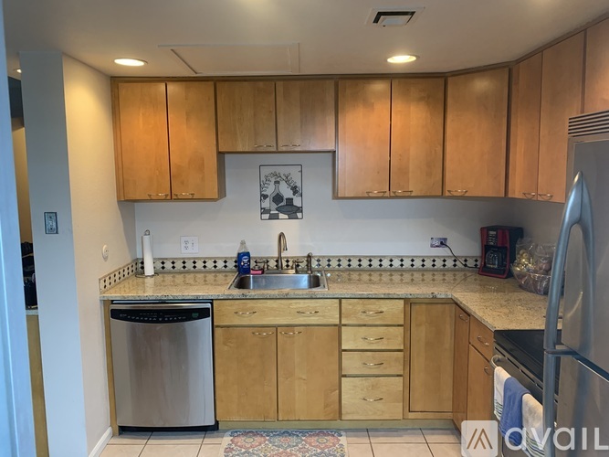 A kitchen with wooden cabinets and a stainless steel dishwasher.
