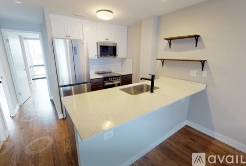 A kitchen with a white countertop and a stainless steel refrigerator.