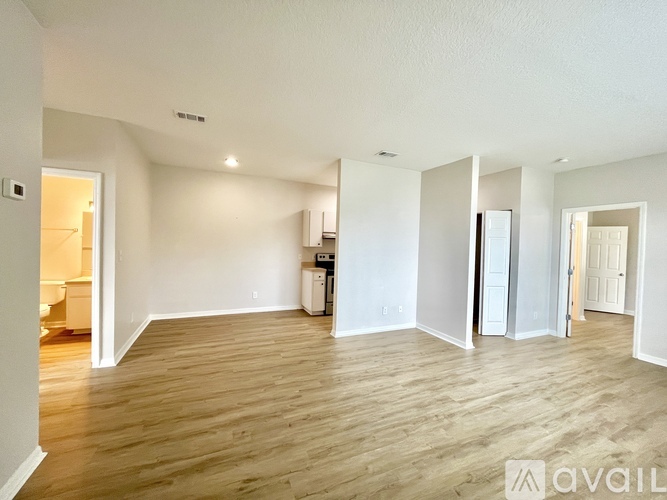 A spacious room with wooden flooring and white walls.