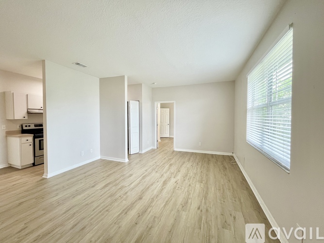 A spacious room with wooden flooring and white walls.