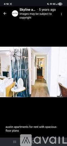 A long hallway with a chair and a table on the left and a door on the right.