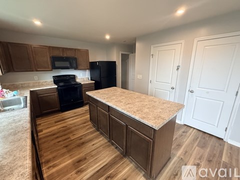 A kitchen with a black refrigerator and wooden floors.
