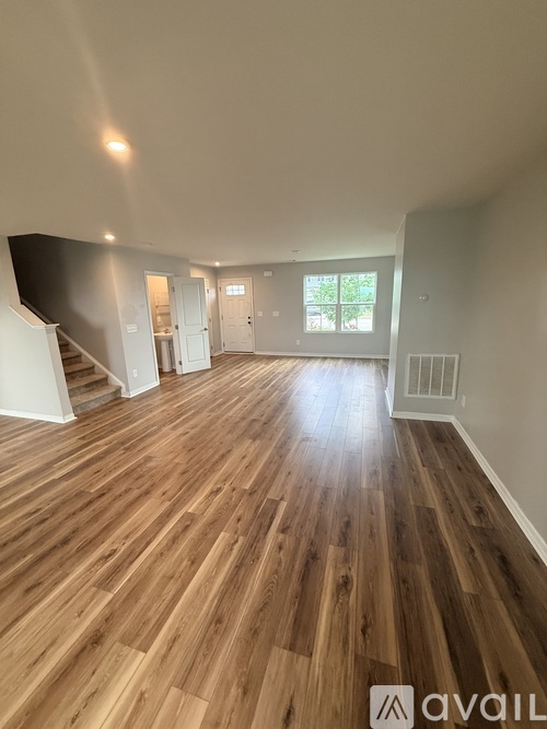 A spacious room with wooden flooring and white walls.