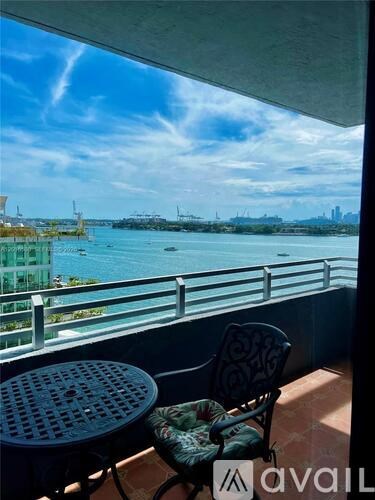 A balcony with a table and chair overlooking a body of water.