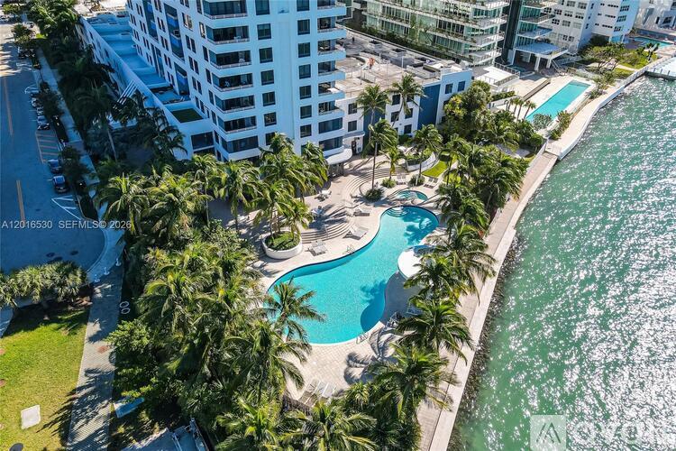 An aerial view of a pool surrounded by palm trees and buildings.
