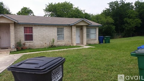 A black trash can with the word SWINDLE on it is in front of a house.