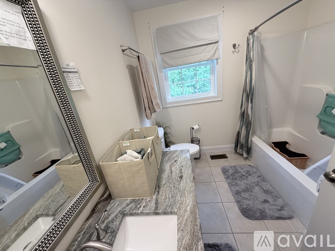 A bathroom with a large mirror, a window with a view of trees, and a shower area.
