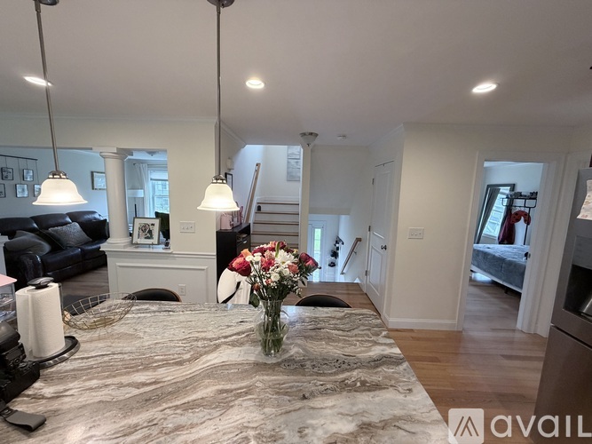 A modern living room with a grey rug and a vase of flowers on the table.