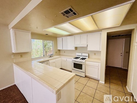 A kitchen with white cabinets and a tiled counter.