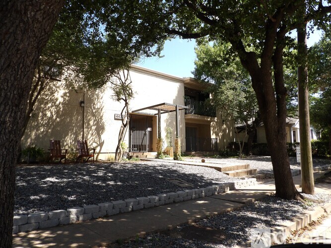 A house with a white exterior and a tree in front of it.