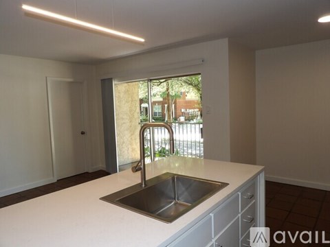 A modern kitchen with a stainless steel sink and white countertops.