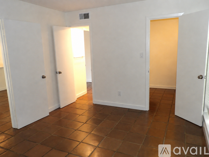 A room with white walls and brown tile flooring.