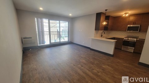 A spacious kitchen and living room with wooden floors and a large window.