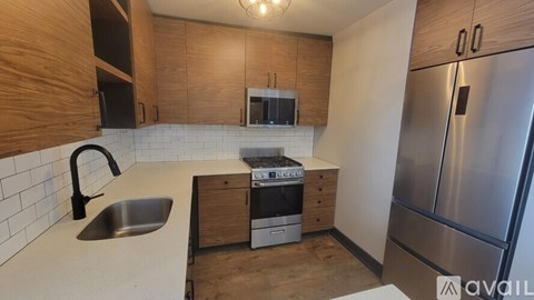 A kitchen with a stainless steel refrigerator and a sink with a black faucet.