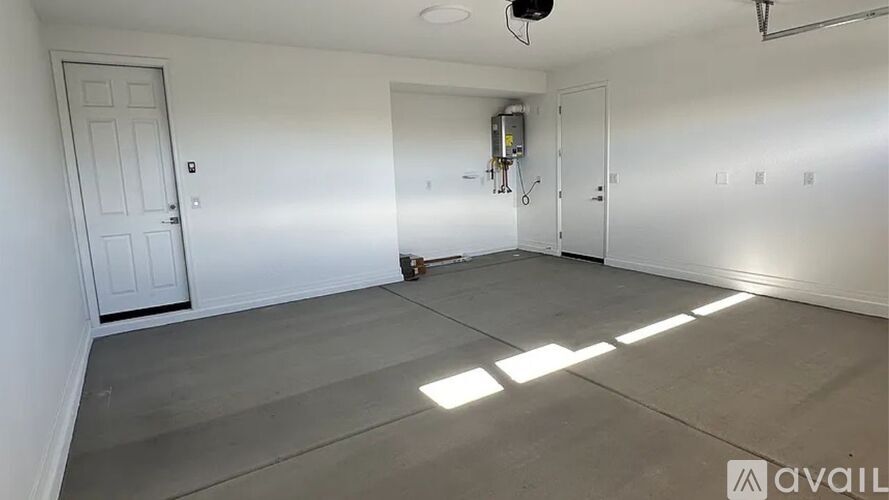 A spacious room with a door on the left and a window on the right.