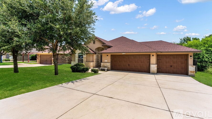A house with a brown garage door is surrounded by greenery.