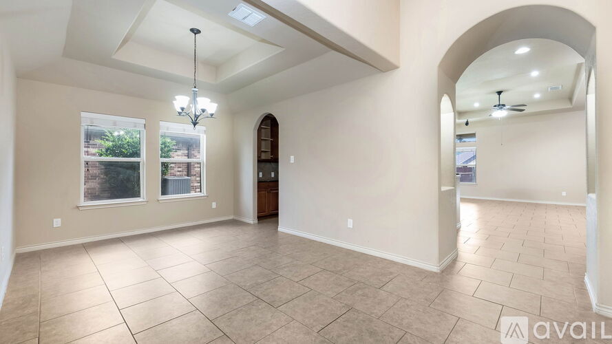 A spacious room with tiled flooring and a chandelier hanging from the ceiling.