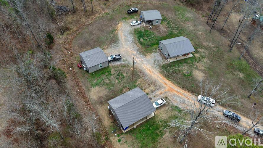 A bird's eye view of a property with four houses and a dirt road.