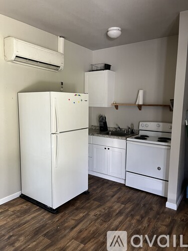 A white refrigerator is in a kitchen with wood floors.