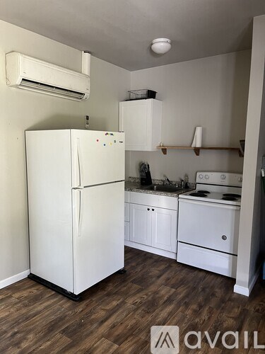 A white refrigerator is in a kitchen with wood floors.