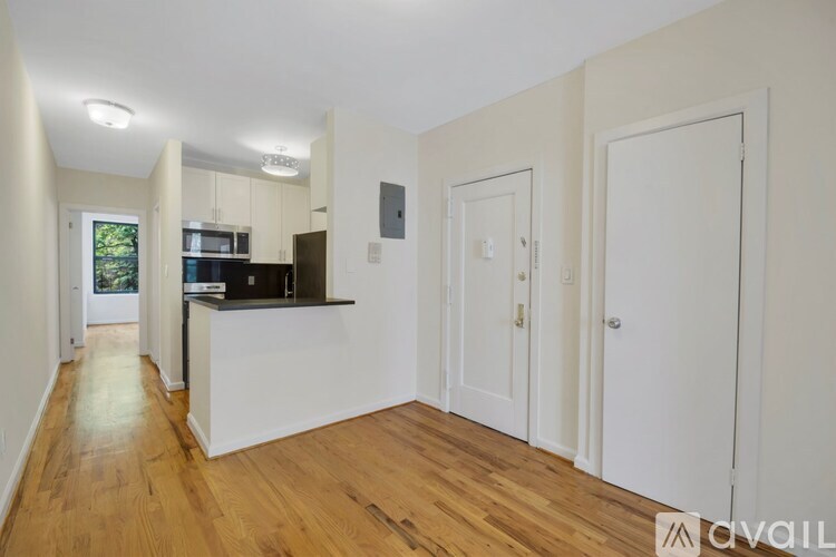 A spacious kitchen with white cabinets and a wooden floor.