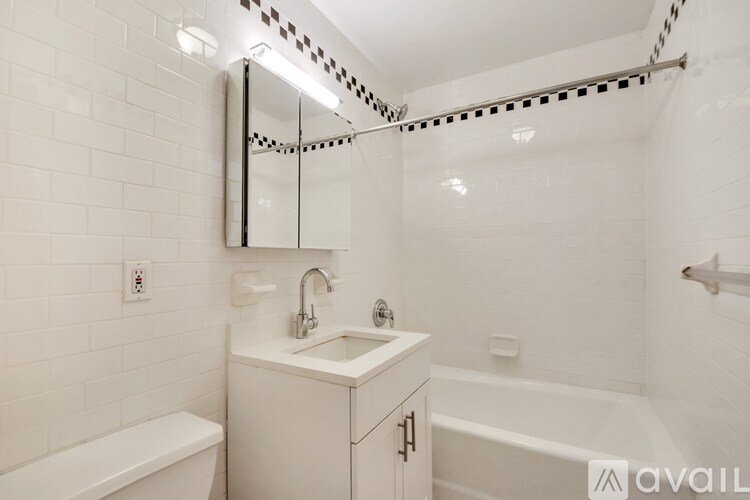 A white bathroom with a sink, mirror, and bathtub.