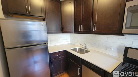 A kitchen with a stainless steel refrigerator and wooden cabinets.