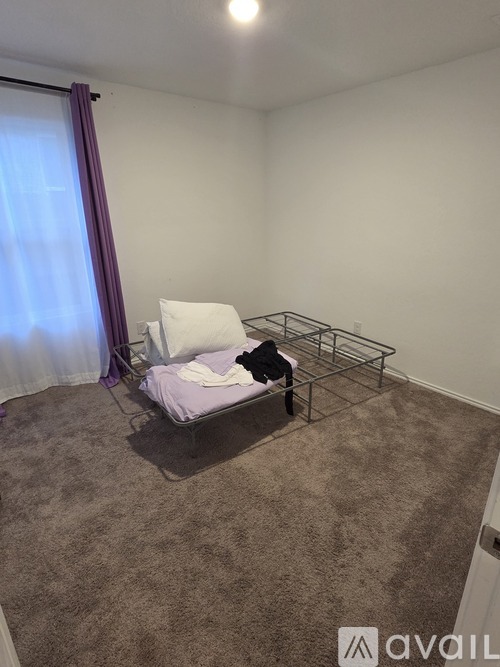 A small bedroom with a bed and a carpet.