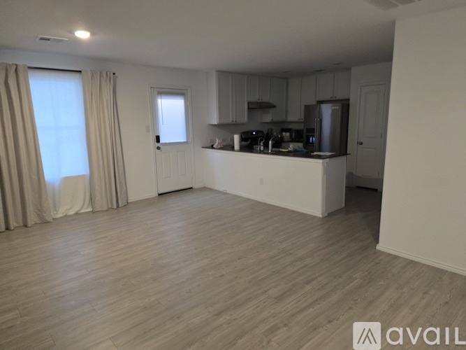 A spacious kitchen with wooden flooring and white walls.